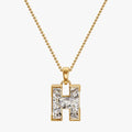 Gold necklace with a diamond-encrusted 'H' pendant on a white background